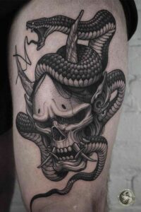 tatuagem de caveira com cobra na coxa